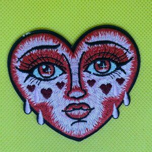 Beautiful embroidered patch featuring a heart-shaped face with vibrant red tones
